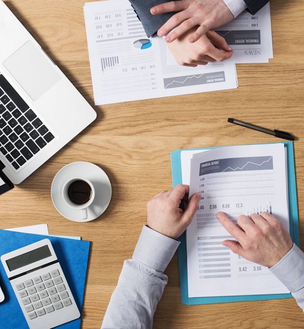 Business people team working together at office desk with laptop, tablet, financial paperwork and reports, top view
